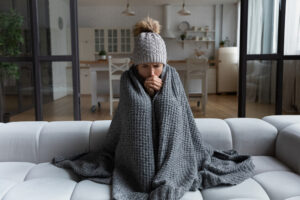 a woman on a couch with a blanket as she is cold, she needs a new furnace.